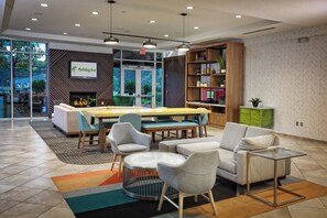 A modern hotel lobby with a fireplace, seating area, and a Holiday Inn sign. - Holiday Inn Statesboro-University Area by IHG (Statesboro)