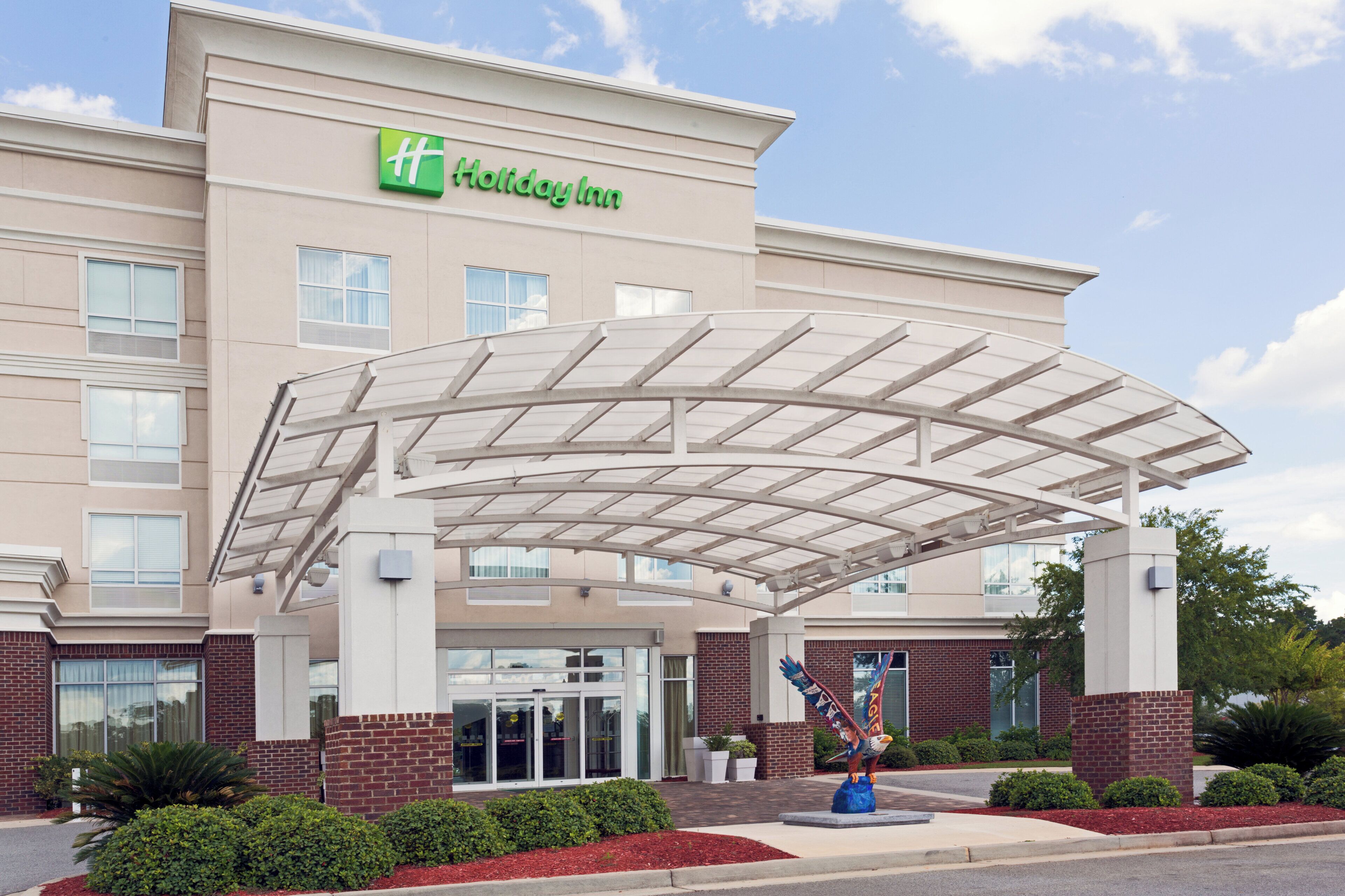A Holiday Inn hotel with a covered entrance and a decorative eagle sculpture.