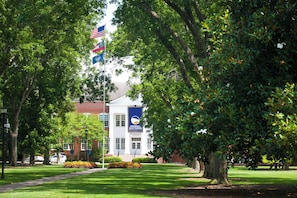 A university campus with a prominent building, a flagpole with flags, and well-maintained landscaping. - Holiday Inn Statesboro-University Area by IHG (Statesboro)