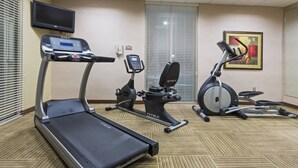 A hotel fitness room with treadmills, stationary bikes, and a TV. - Holiday Inn Statesboro-University Area by IHG (Statesboro)