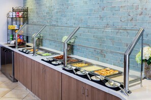 A buffet setup with various food items and a beverage station. - Holiday Inn Statesboro-University Area by IHG (Statesboro)