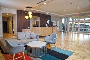 Área de recepção com assentos, balcão de atendimento e entrada em vidro.