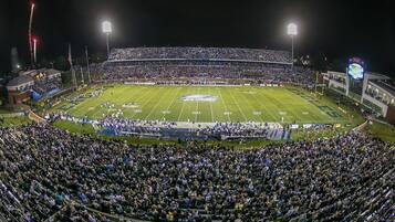 A stadium with multiple tiers of seating, a football field, and a large crowd.