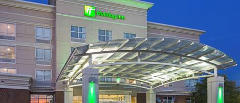 A Holiday Inn hotel with a covered entrance, multiple windows, and a brick facade.