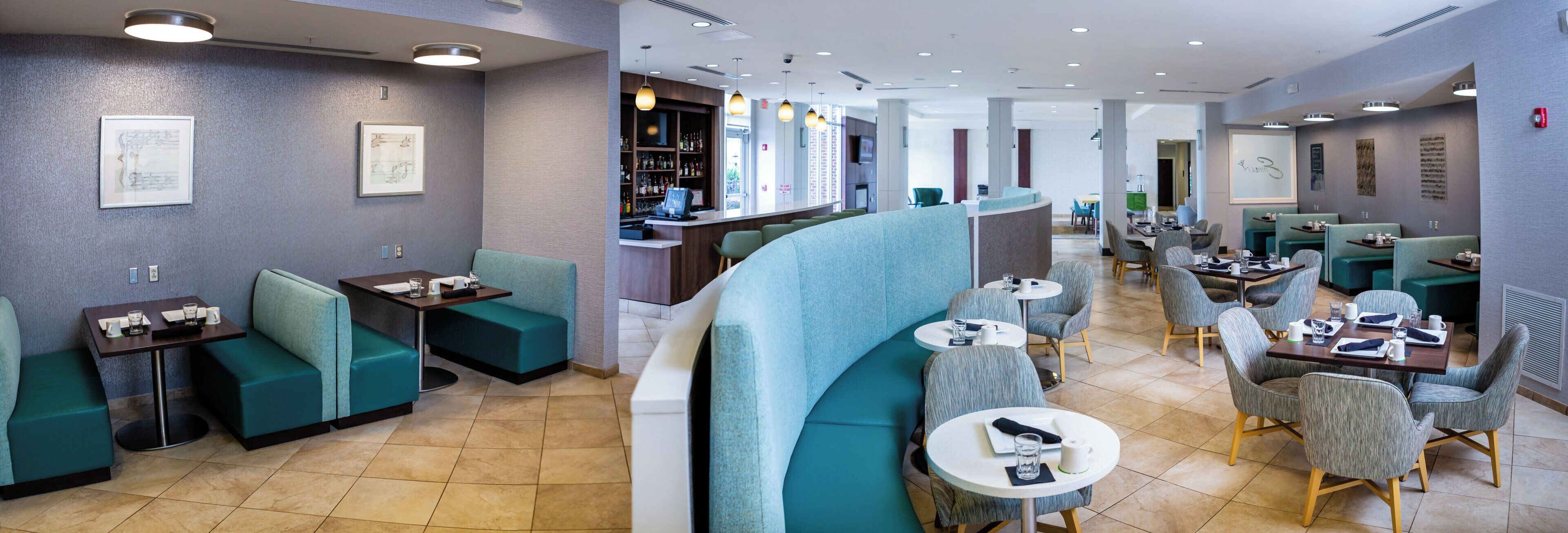 Un restaurant moderne avec des sièges de couleur turquoise, un bar et une vue sur la ville.