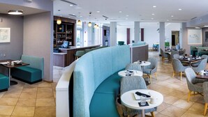 A modern restaurant with teal seating, a bar area, and a view of the city. - Holiday Inn Statesboro-University Area by IHG (Statesboro)