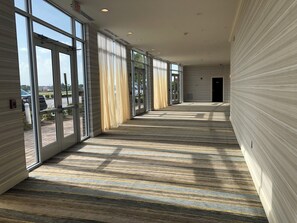 A hallway with large windows, a striped floor, and a fire alarm on the wall. - Holiday Inn Statesboro-University Area by IHG (Statesboro)