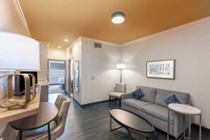 A hotel room with a sofa, a small table, a lamp, and a chair. - Holiday Inn & Suites McKinney - N Allen by IHG (McKinney)