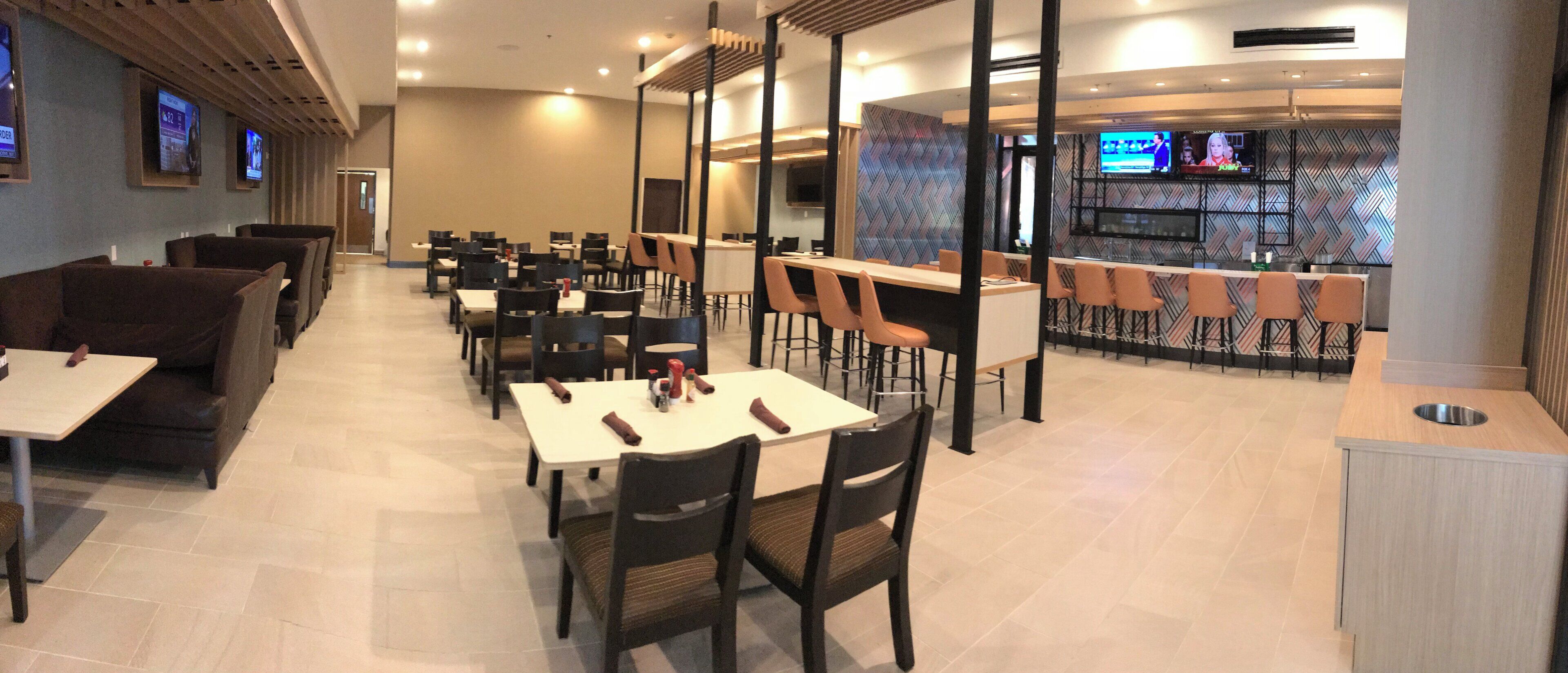 Un restaurant doté de nombreuses tables et chaises, d’un bar et de téléviseurs fixés aux murs.