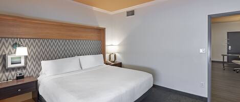 Une chambre d’hôtel avec un lit, une table de chevet, une lampe et une vue sur le couloir.
