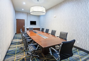 A conference room with a long table, chairs, a television, and patterned carpet. - Holiday Inn & Suites McKinney - N Allen by IHG (McKinney)