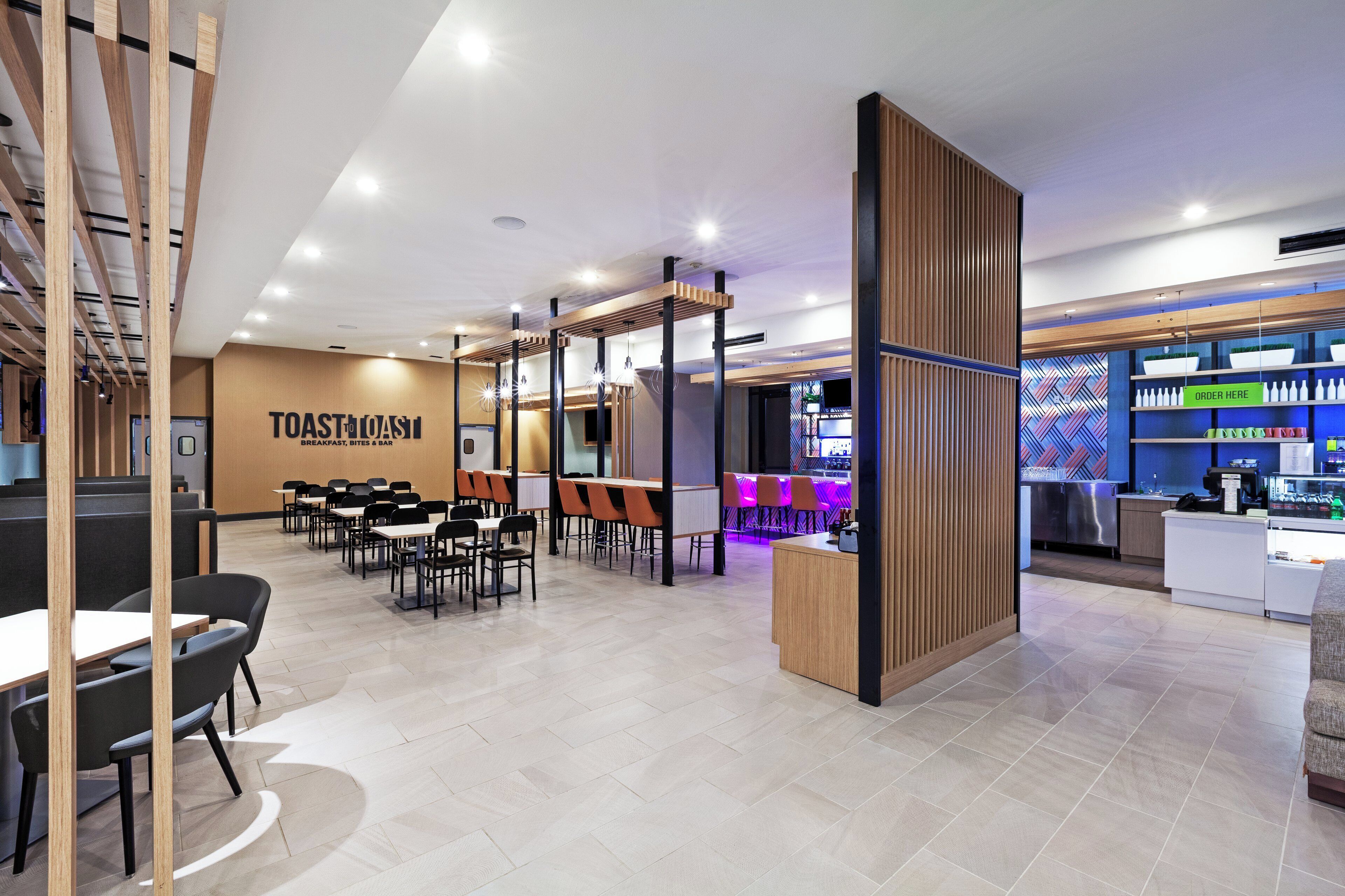Een modern restaurant met een bar, zitplaatsen en een zichtbaar menubord.