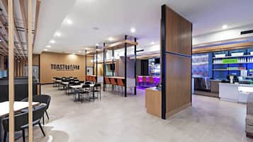 A modern restaurant with a bar area, seating arrangements, and a visible menu board.