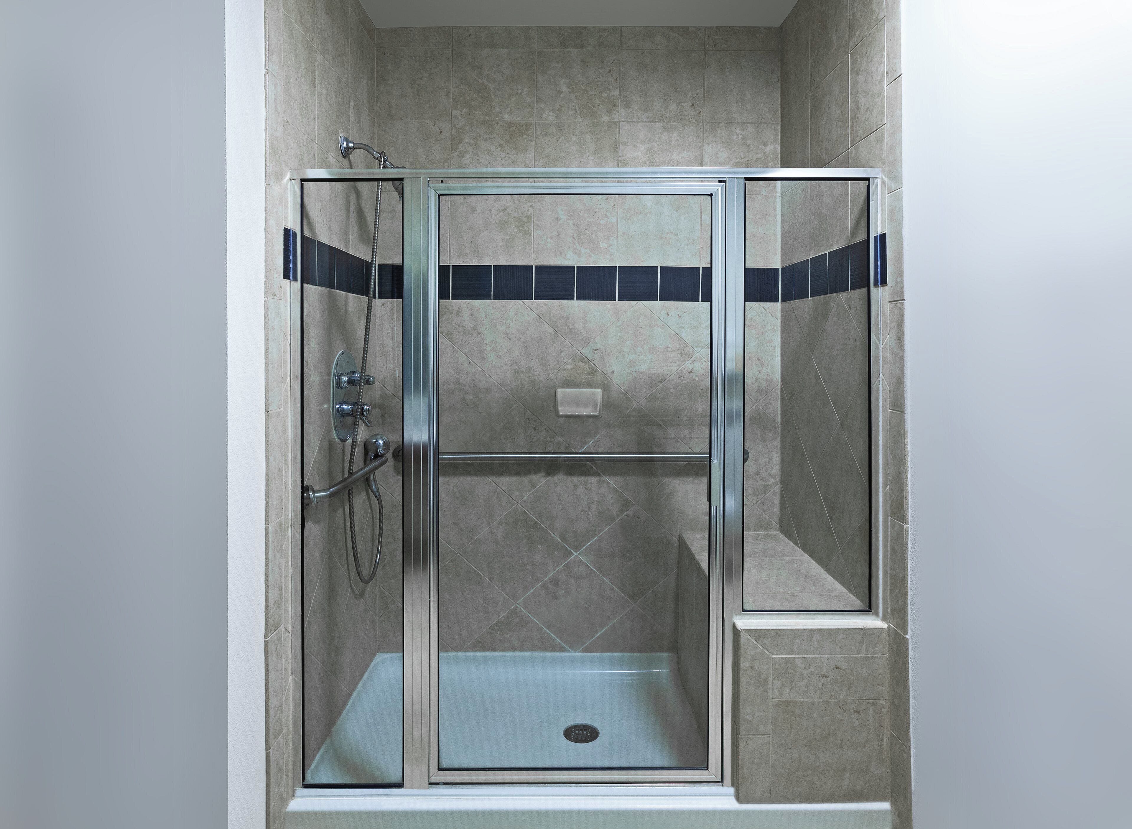 A glass-enclosed shower stall with a tiled floor and a showerhead.