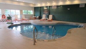 Ein Innenpool mit klarem Wasser, umgeben von Liegestühlen und einer gefliesten Wand.