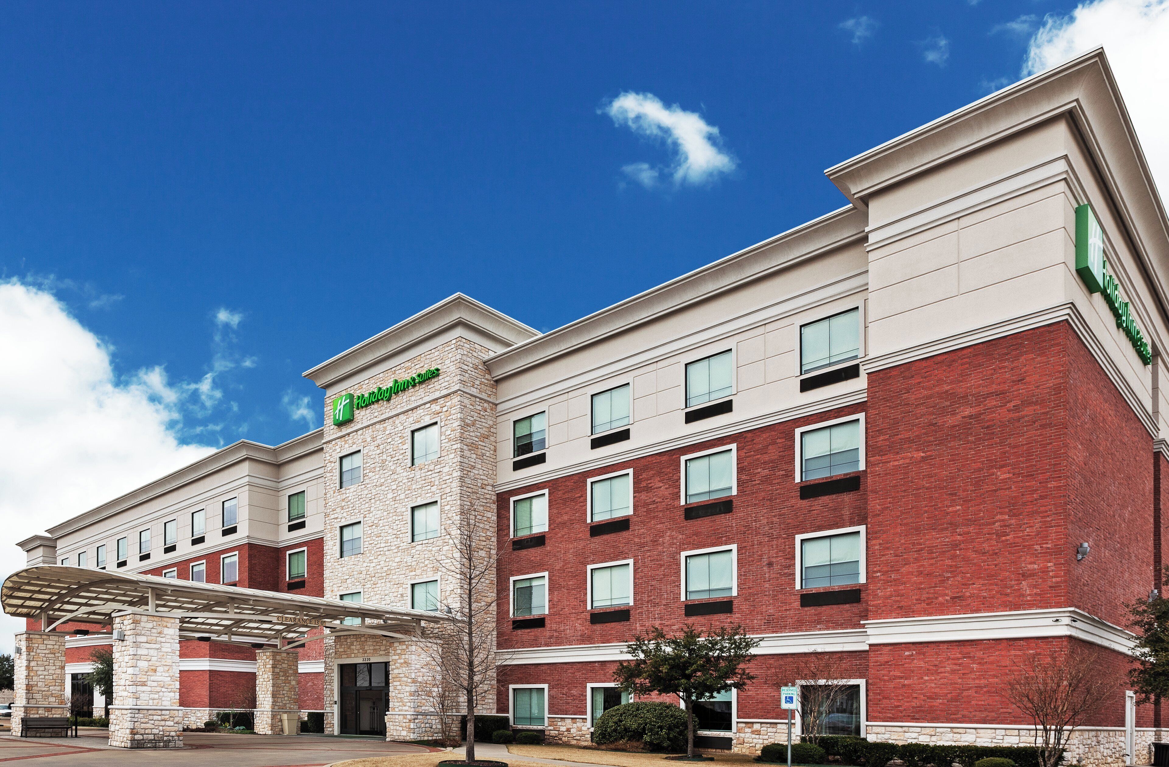 A Holiday Inn Express hotel with a brick facade, multiple windows, and a clear sky.