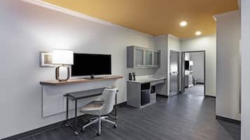 A modern office space with a desk, chair, television, and cabinets.