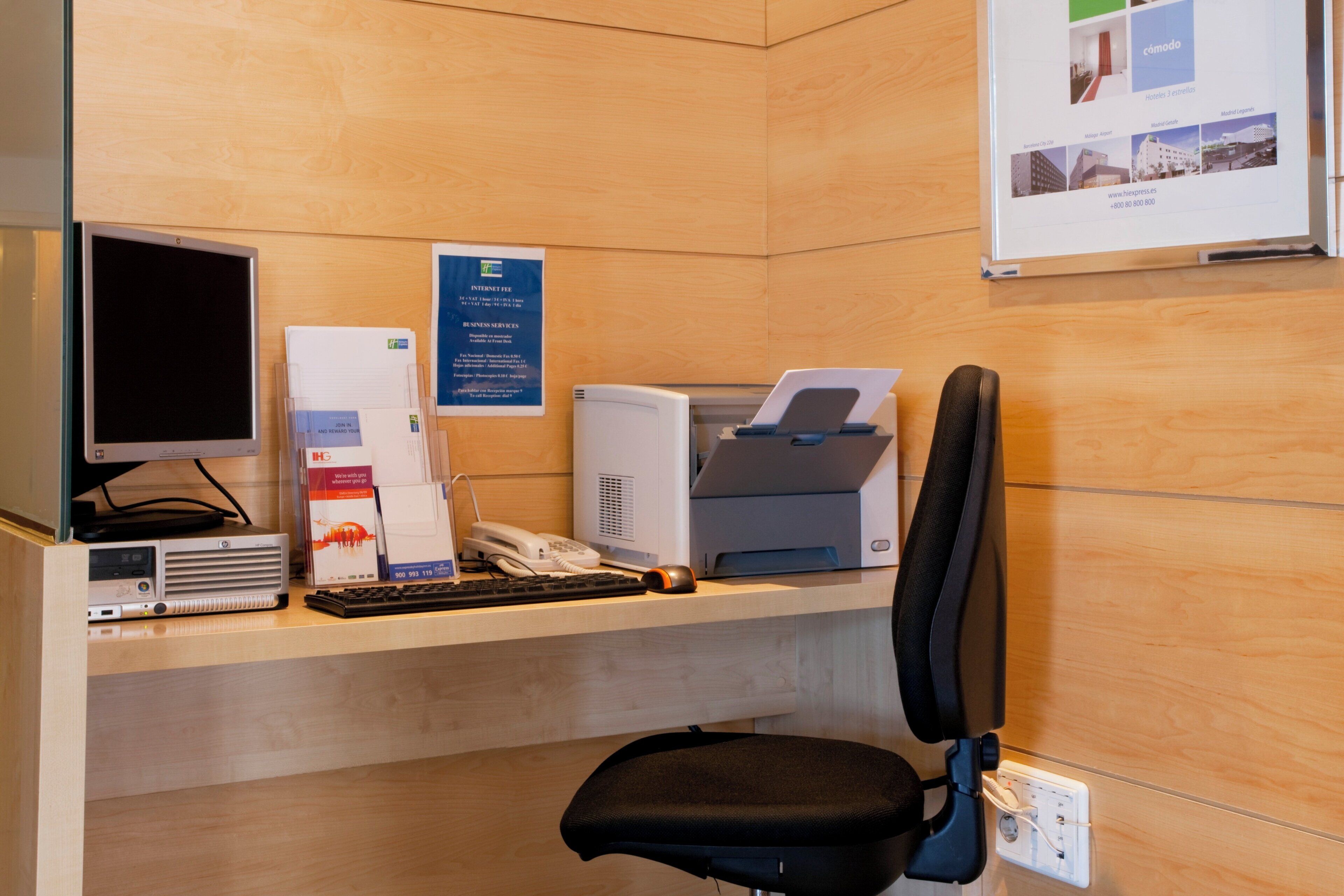 Un mostrador de recepción de hotel con computadora, impresora y teléfono.