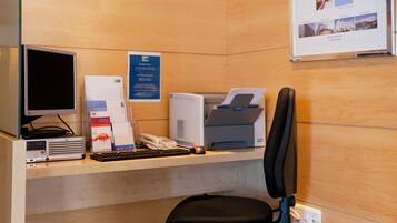 Un mostrador de recepción de hotel con computadora, impresora y teléfono.