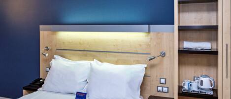 A hotel room with a bed, a nightstand, a wooden wardrobe, and a coffee maker.