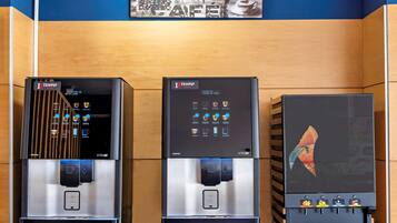Tres máquinas de café con interfaces digitales, una pared de madera y una obra de arte con temática de café.