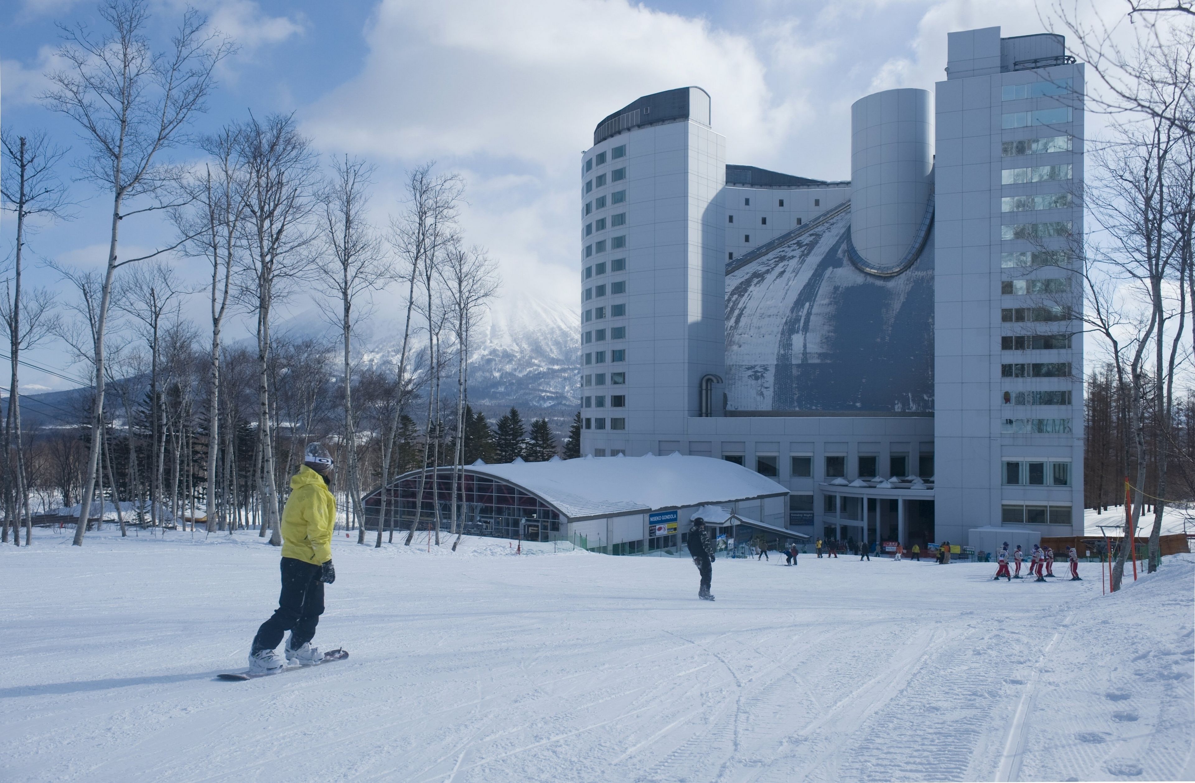 Une station de ski avec un grand bâtiment doté d’un toit incurvé et de nombreuses fenêtres.