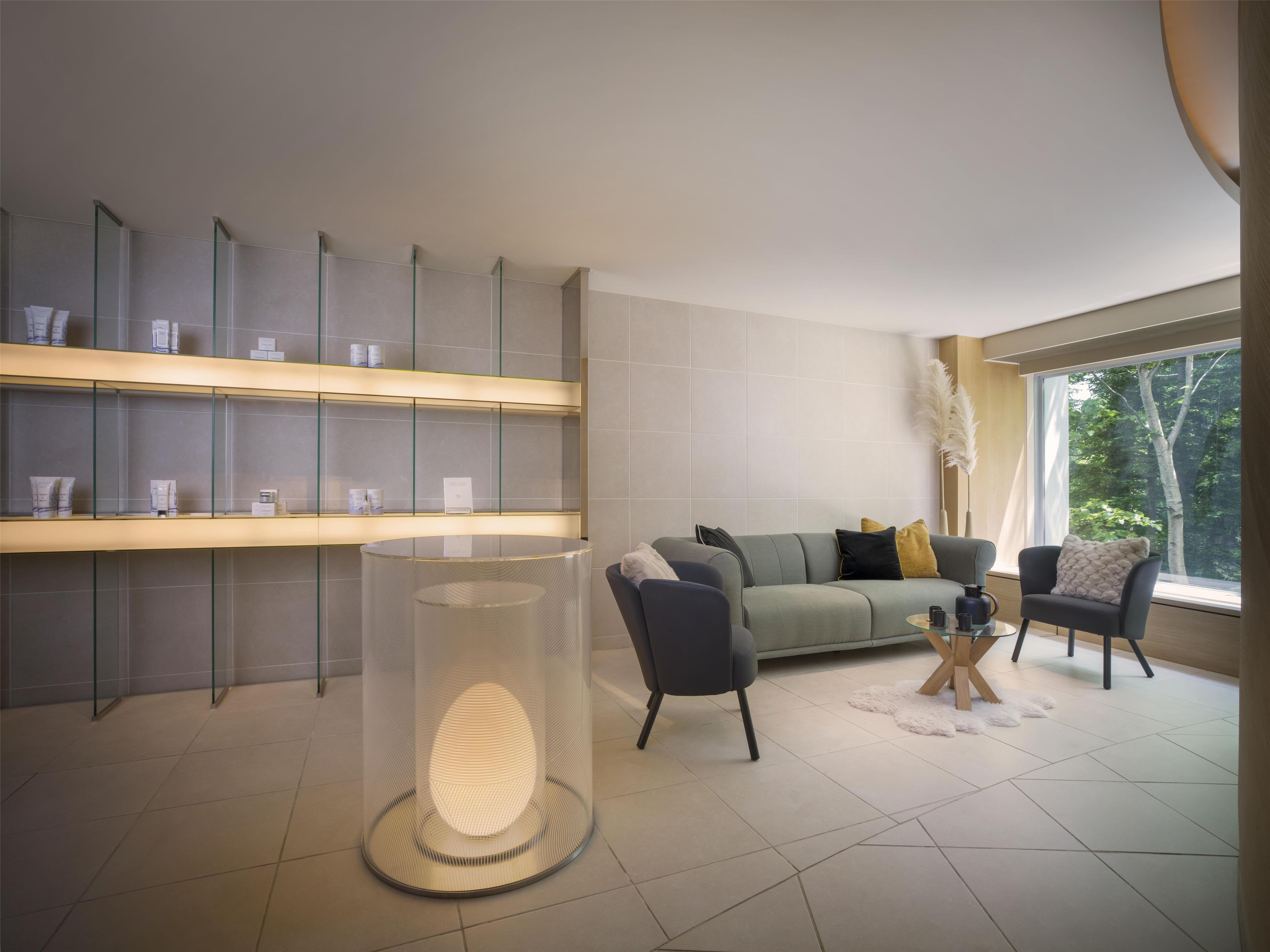 A modern living room with a sofa, armchairs, a glass table, and a decorative floor lamp.