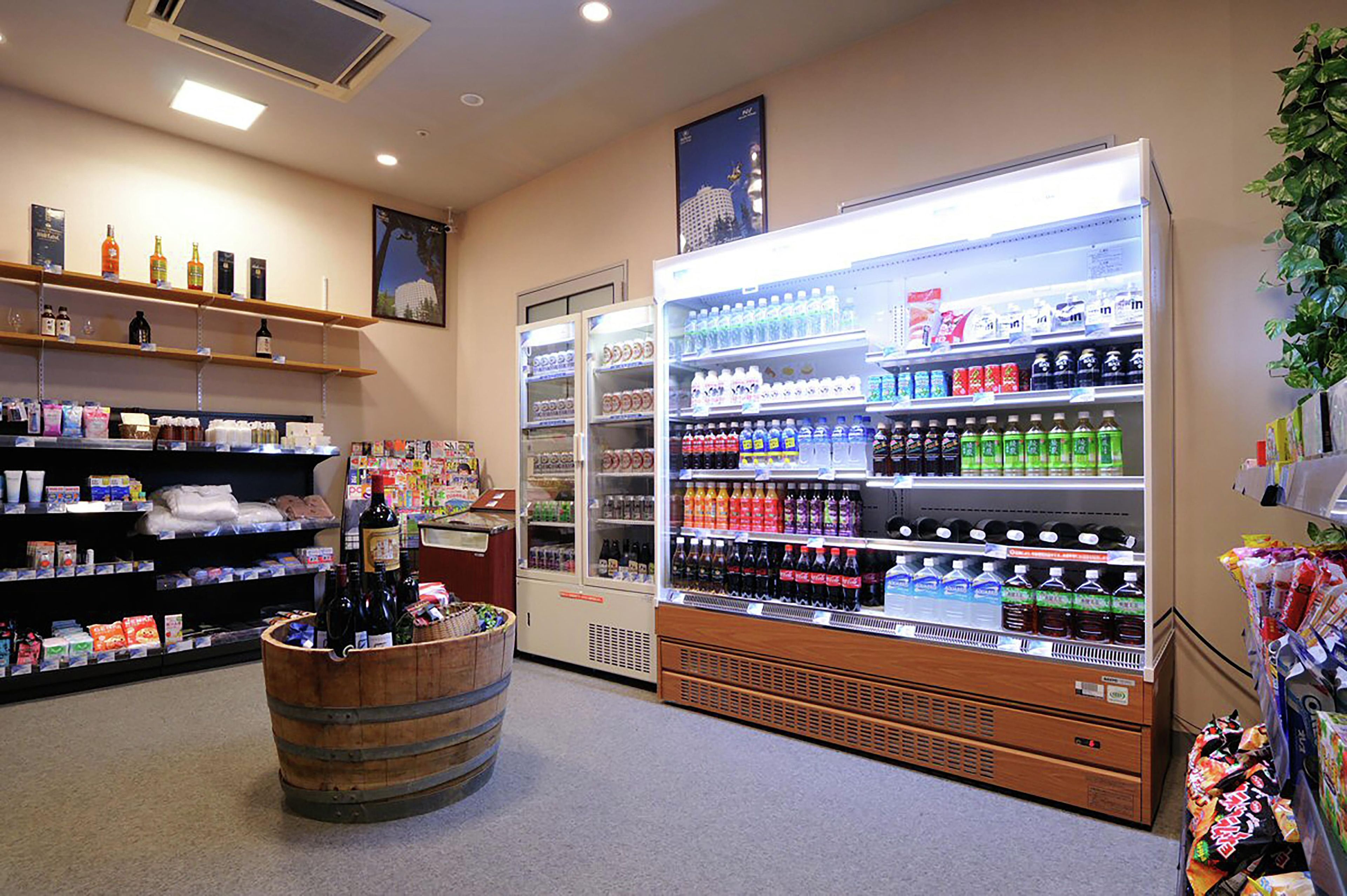 A store interior with shelves stocked with various beverages, a refrigerated section, and a wooden barrel.