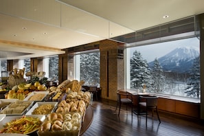 A buffet with a variety of food items and a view of a snow-covered mountain. - Hilton Niseko Village (Niseko)