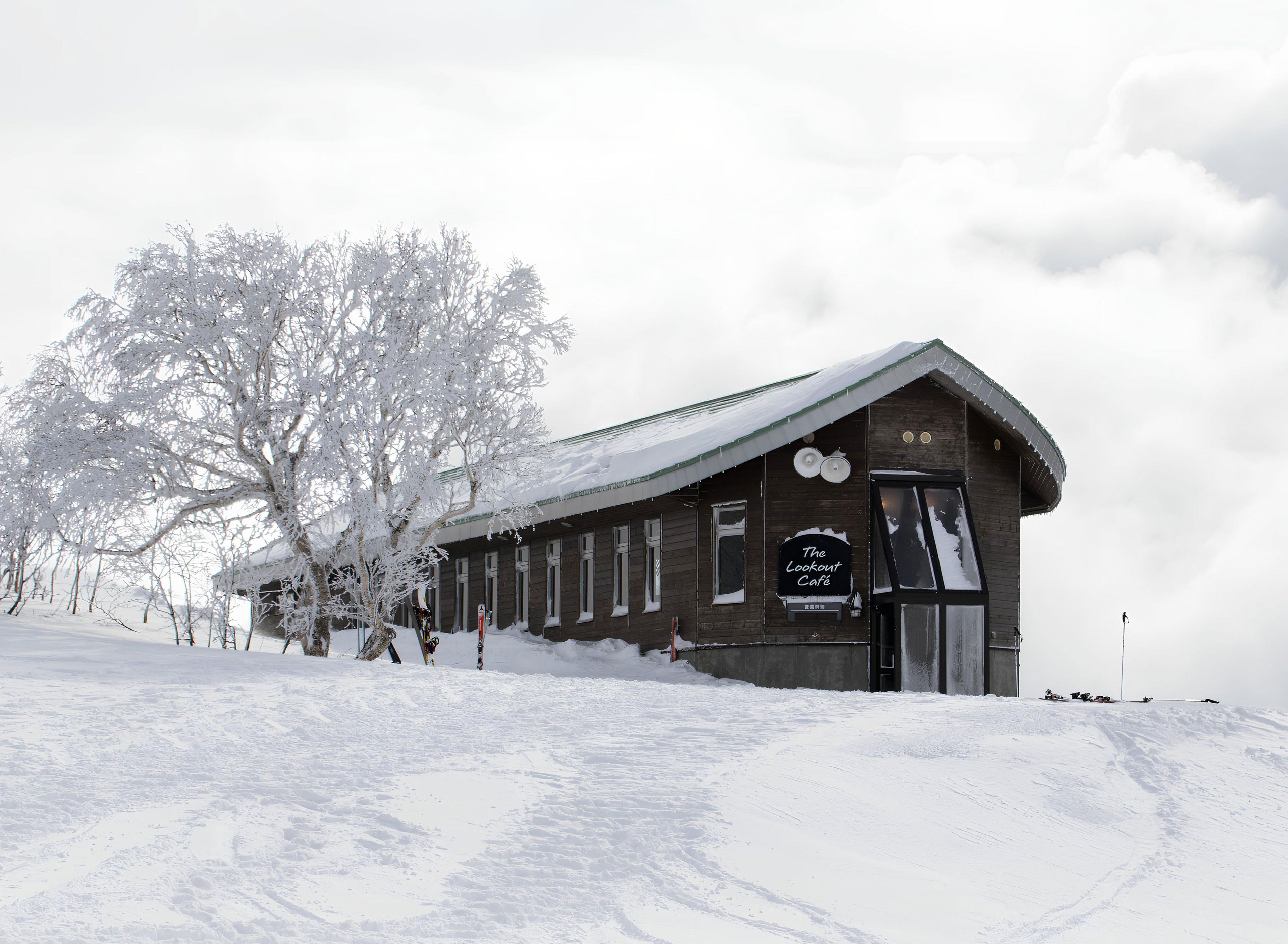 A wooden building with a sign reading "The Lookout Café" in a snowy landscape.