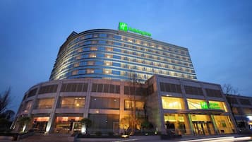 Ein mehrstöckiges Hotel mit einer geschwungenen Fassade, großen Fenstern und einem auffälligen grünen Logo.