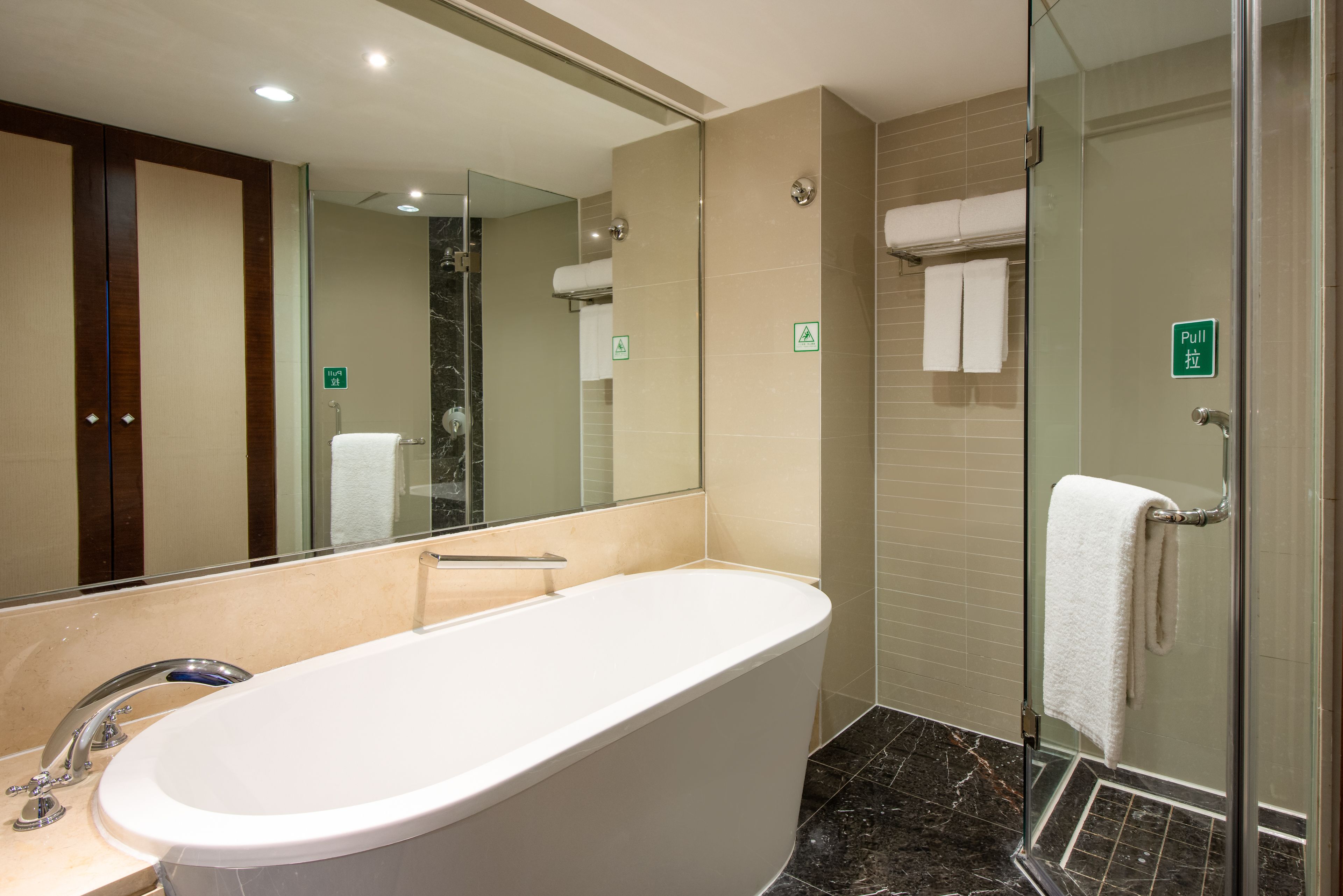 Ein modernes Badezimmer mit einer freistehenden Badewanne, einer Duschkabine aus Glas und einem großen Spiegel.