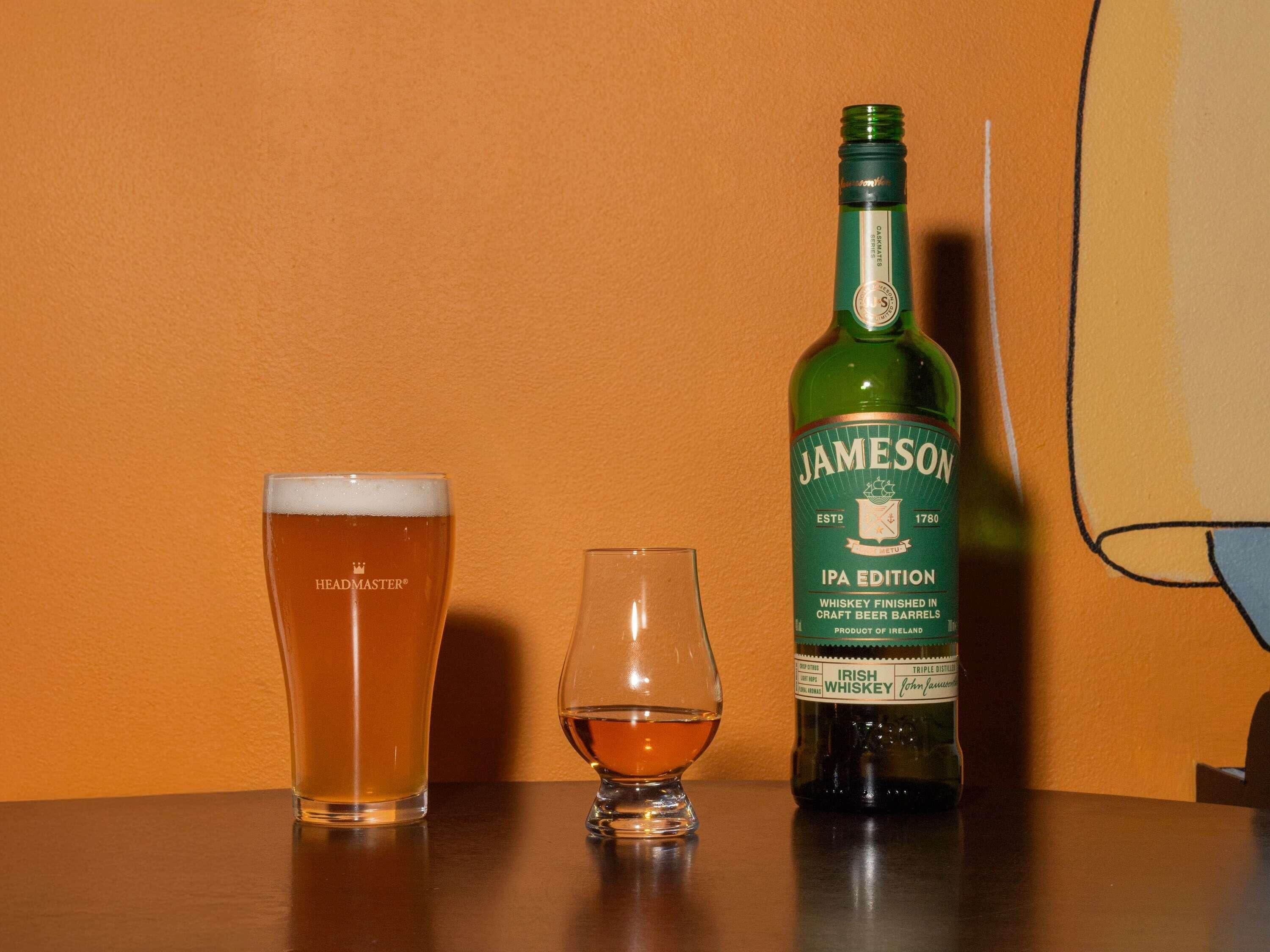 Un verre de bière, une bouteille de whisky et un verre vide sur une table.