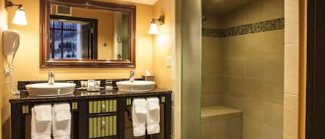 A bathroom with two sinks, a mirror, and a shower area.
