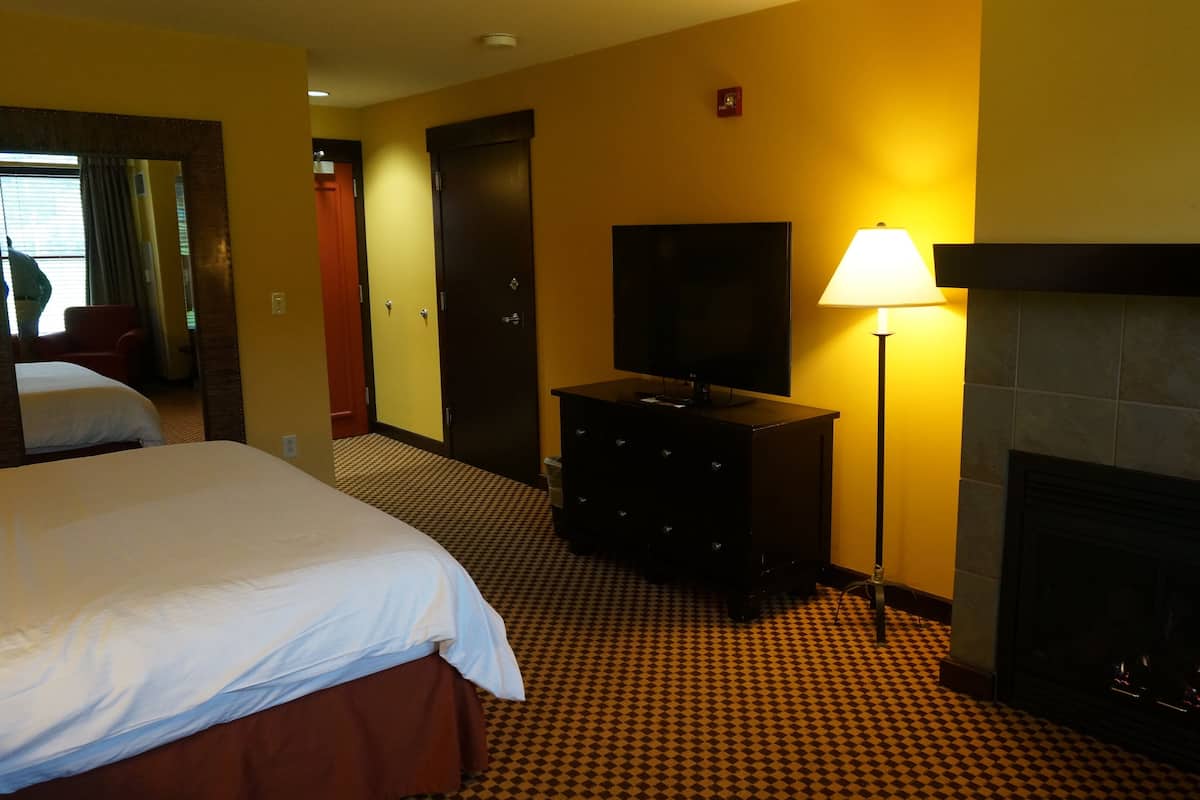 Een hotelkamer met een bed, een kaptafel, een televisie, een lamp en een open haard.