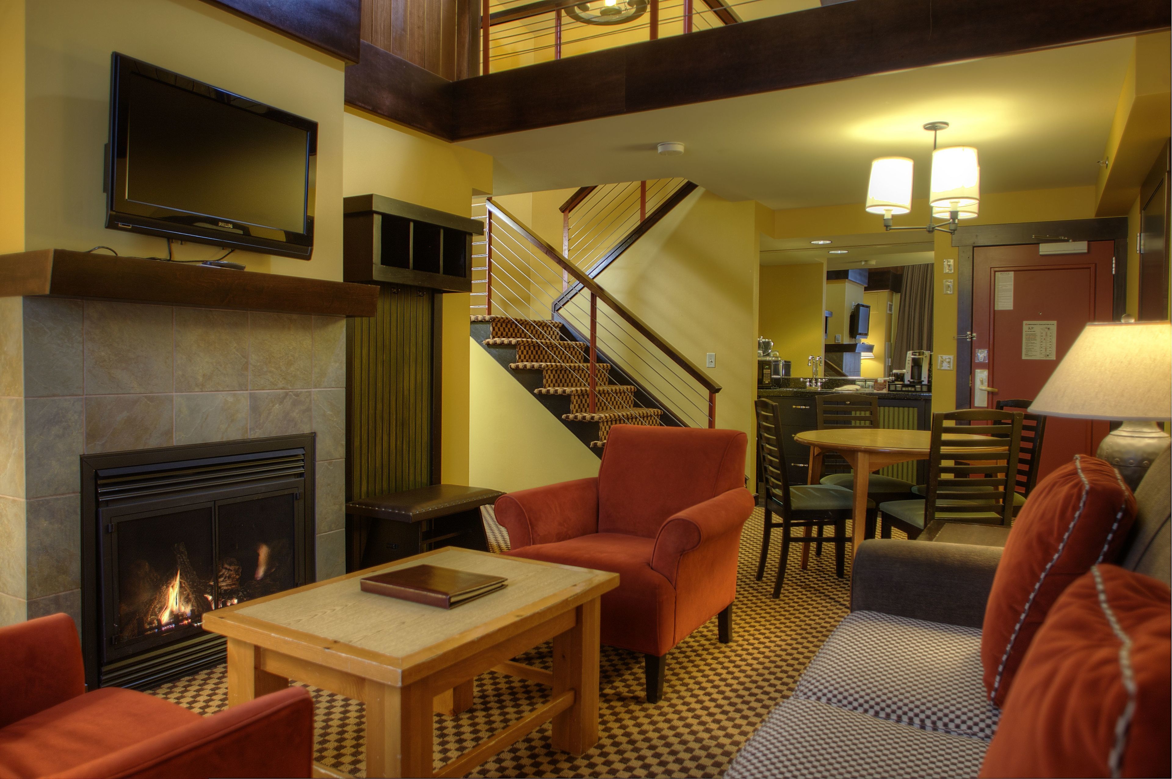 Un hall d’hôtel doté d’une cheminée, d’un espace salon, d’un escalier et d’un téléviseur fixé au mur.