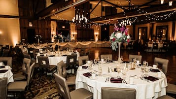 A banquet hall with round tables set for a formal event, featuring white tablecloths, chairs, and centerpieces.