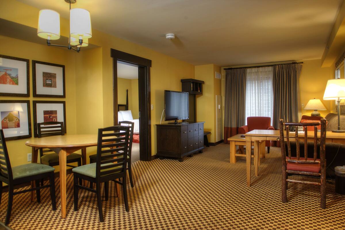 Een hotelkamer met een zithoek, een televisie op een dressoir en een kamerbreed tapijt met dessin.