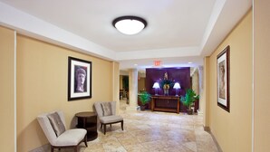 A lobby with two armchairs, a reception desk, and framed artwork on the walls.