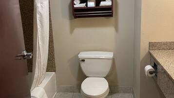 Un baño con inodoro, toallero encima y cortina de ducha parcialmente visible.