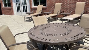 An outdoor patio with a round metal table and six beige cushioned chairs. - Holiday Inn Express Hotel & Suites Niagara Falls by IHG (Niagara Falls)