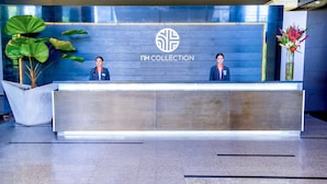 Un comptoir d’accueil orné du logo « NH COLLECTION » et où se trouvent deux employés.