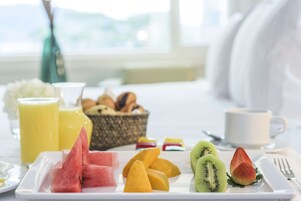 Ein Frühstückstisch mit einer Schale Obst, einem Korb mit Gebäck und einer Tasse Kaffee.