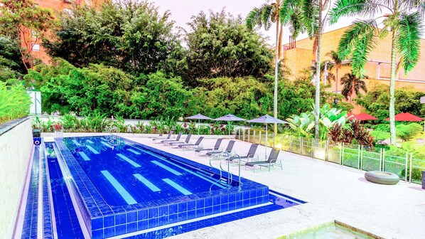 Una piscina al aire libre, sombrillas, tumbonas