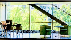 Un hall d’entrée spacieux avec un plafond haut, un escalier et un espace détente comprenant des chaises et une table.