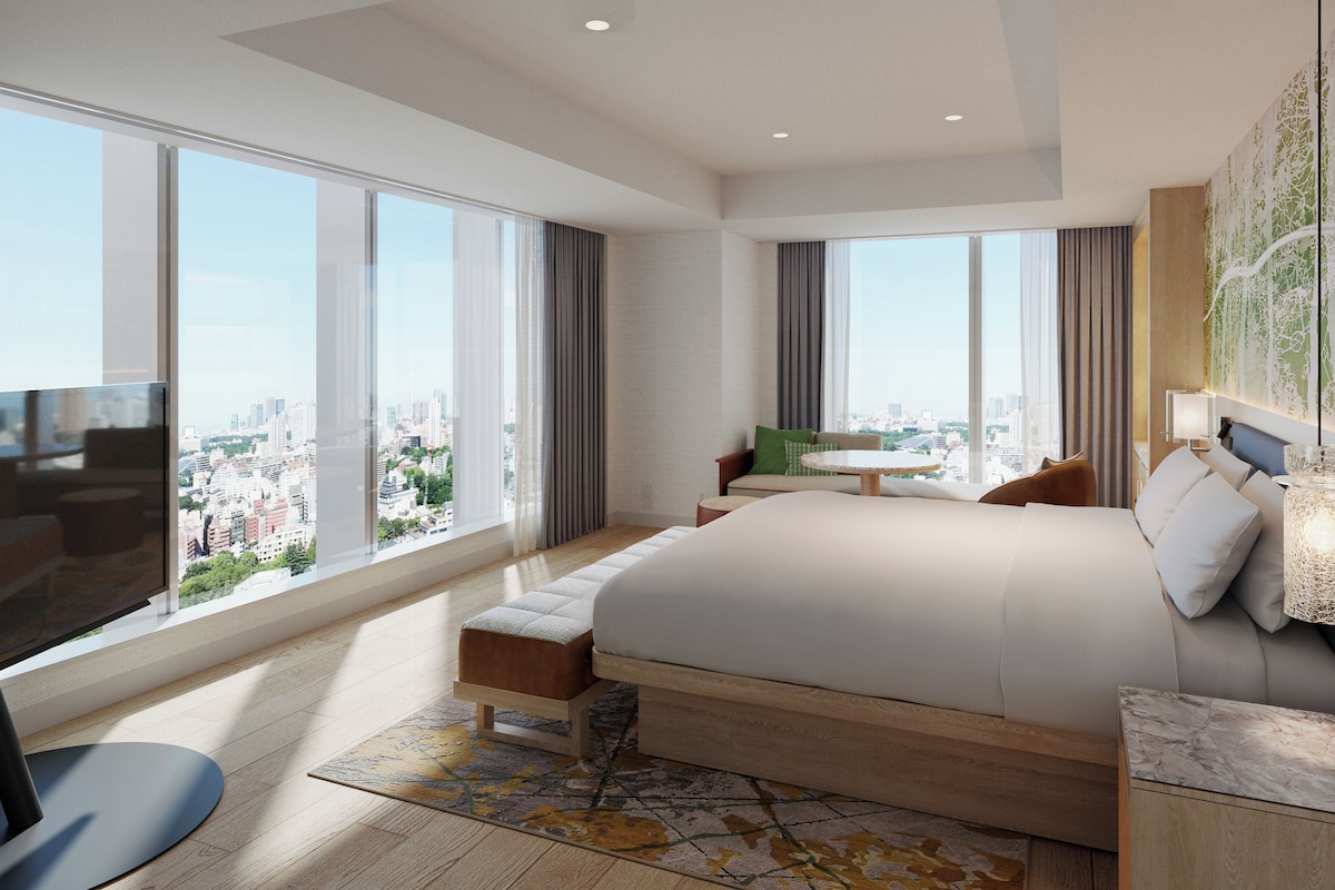 A modern hotel room with a large bed, a desk, and a view of the city.