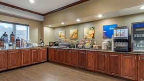 A hotel breakfast area with wooden cabinets, a coffee machine, and a fruit display. - Comfort Suites Near Texas A&M University - Corpus Christi (Corpus Christi)