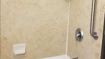 Ein Badezimmer mit Badewanne, Handbrause, Haltegriff und Seifenschale.