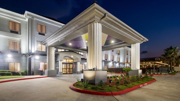 A hotel entrance with a covered walkway, columns, and a well-lit facade.