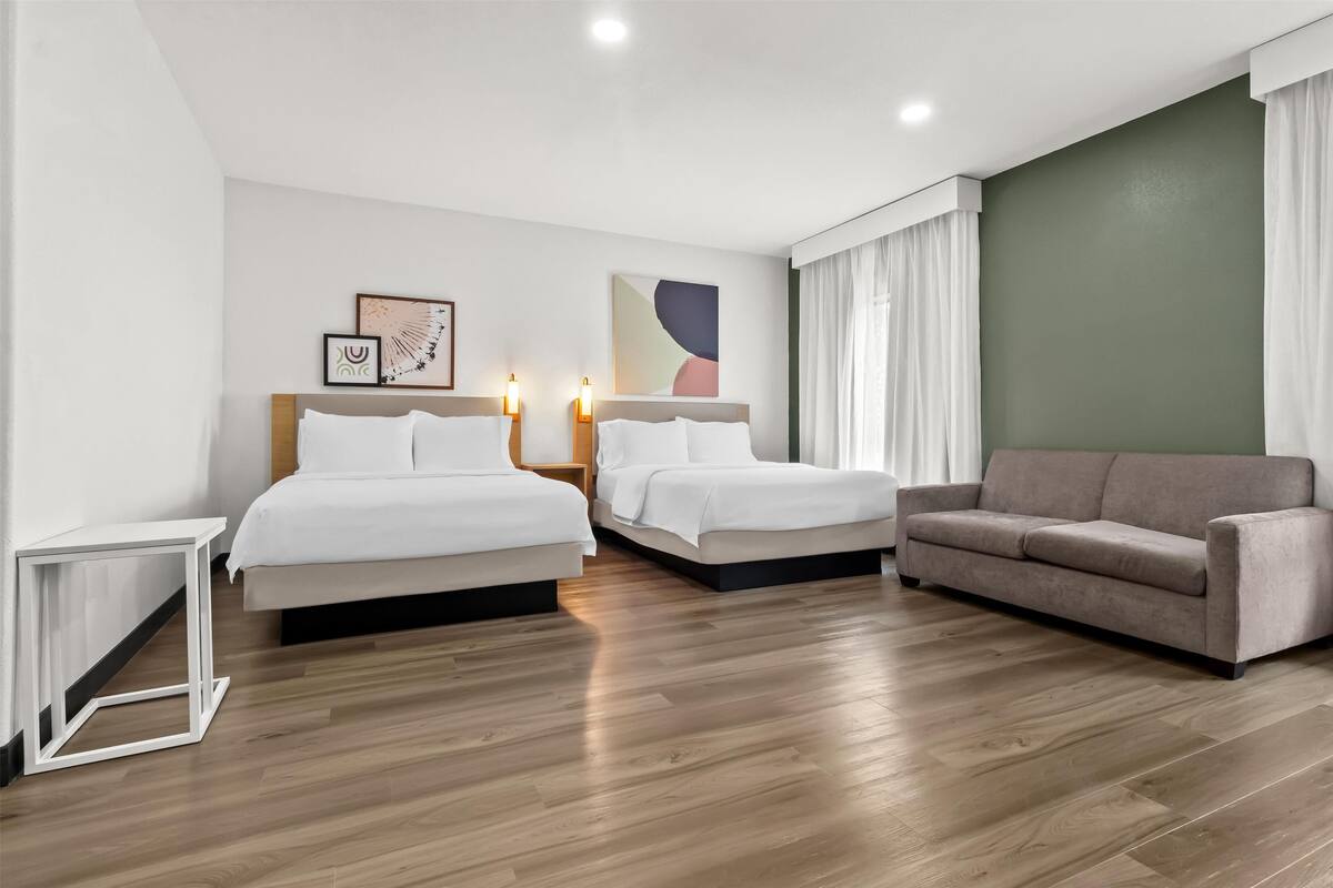 Une chambre d’hôtel avec deux lits, un canapé et une petite table.